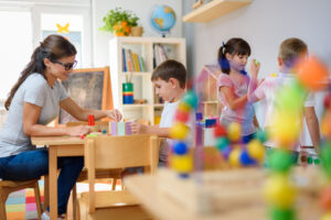 prekindergarten teacher with children playing with colorful wooden toys