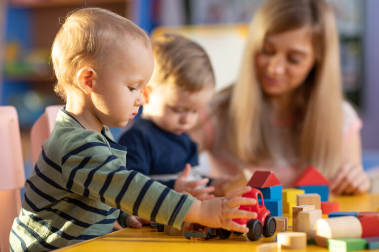 preschool teacher and young toddlers play at daycare