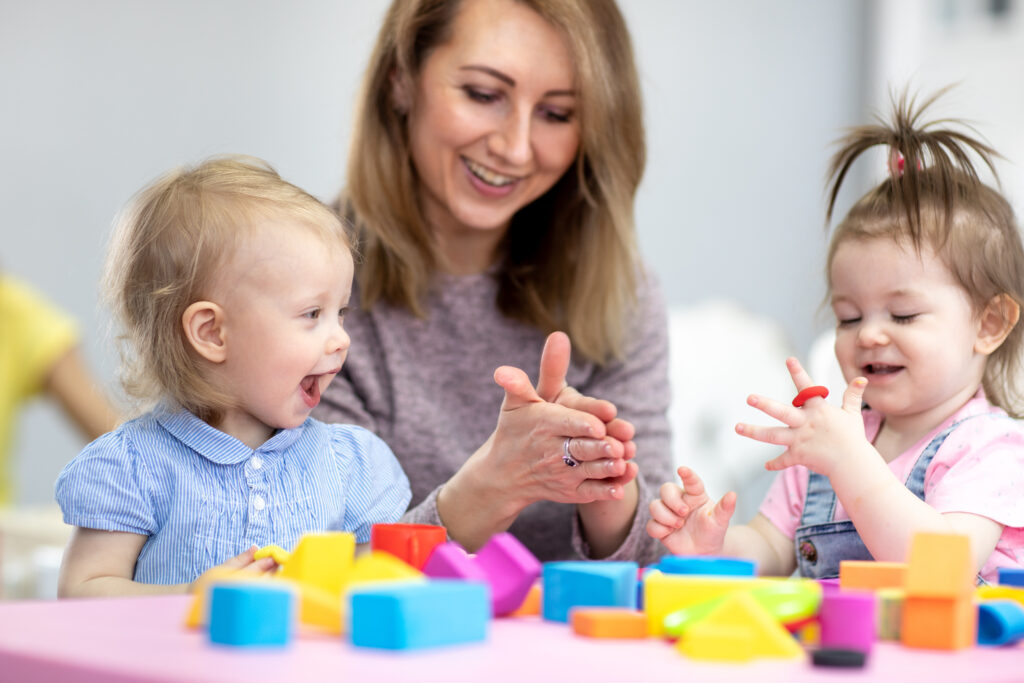 teacher and toddlers play with clay toys at day care center