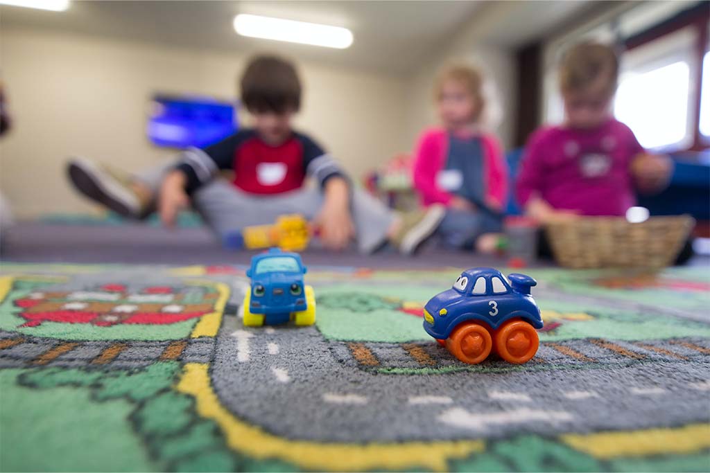 students on a road rug playing with toy cars