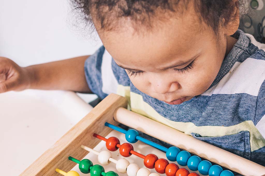 young toddler playing with wood bead toy