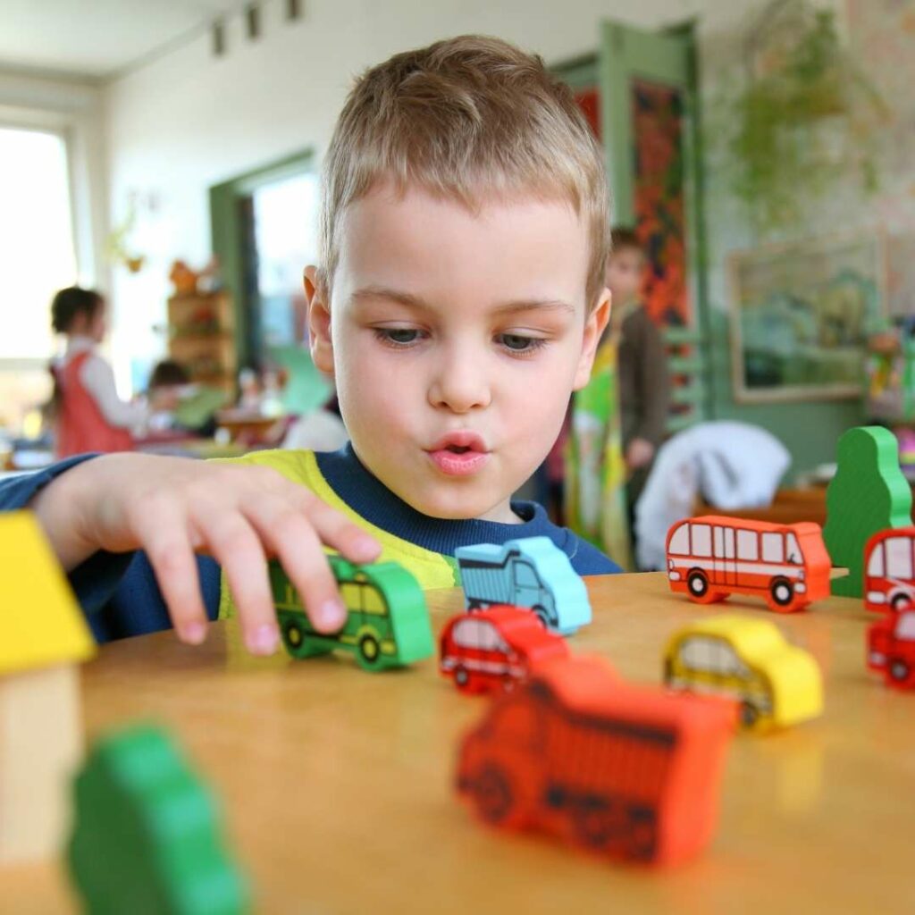 Boy playing with wooden cars on a table