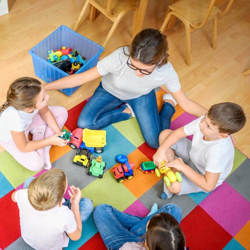 Woman and children sitting on a mat playing with toys