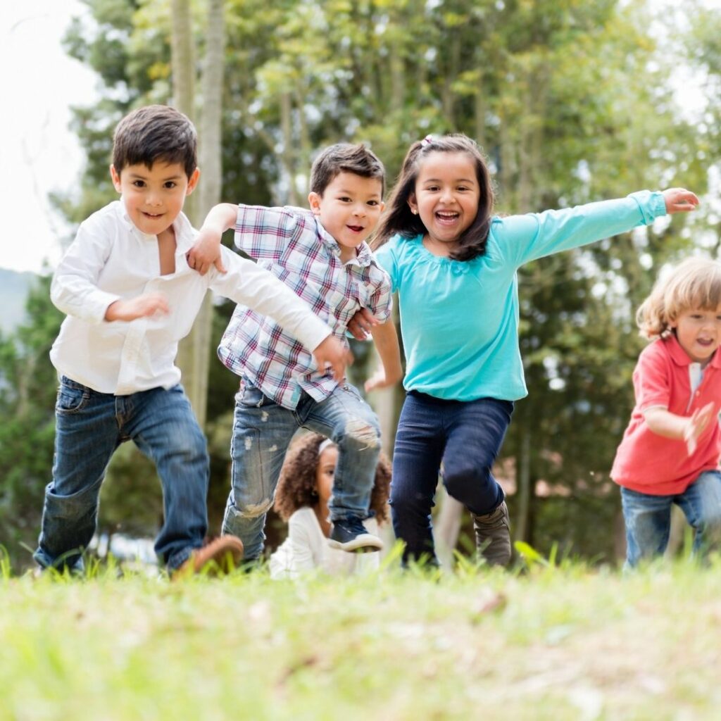 children running in a field with bubbles