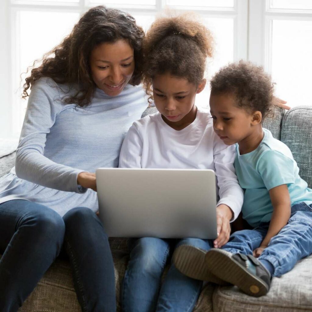 Mother and two children sitting on the couch looking at a laptop