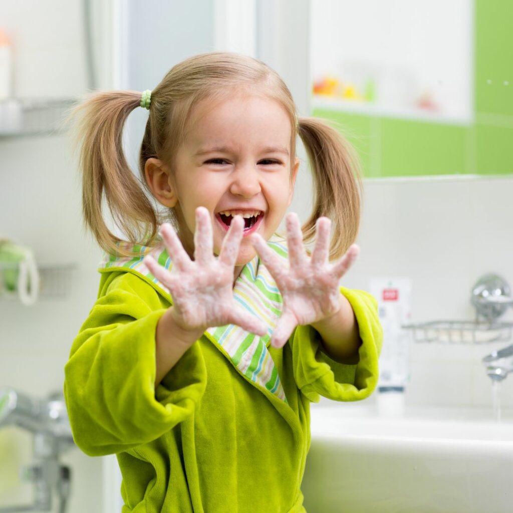 Young girl with soap on her hands, smiling.