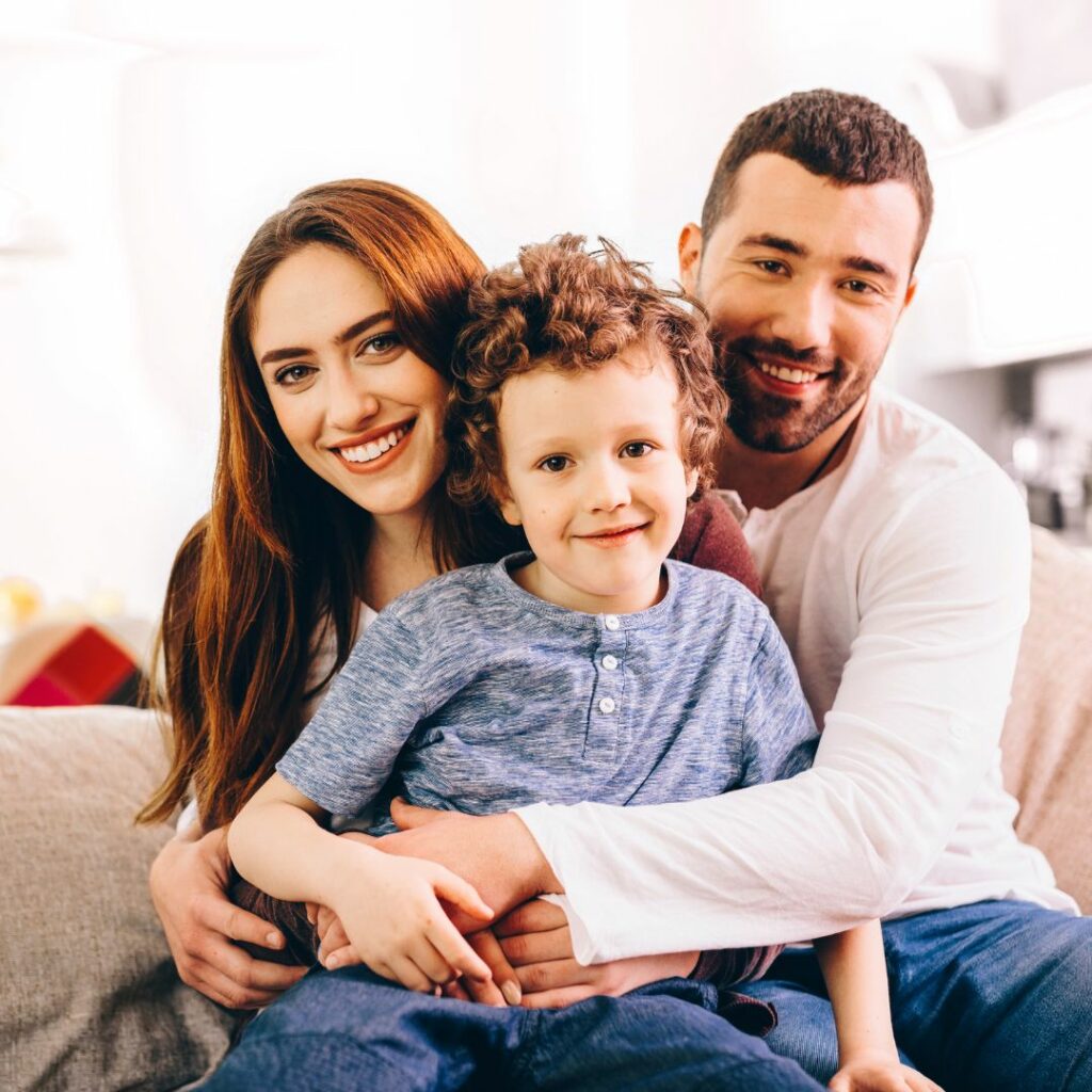 Man and a woman holding their son in their laps, smiling. 